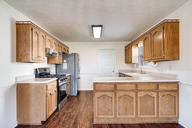 kitchen with a textured ceiling, gas stove, sink, dark hardwood / wood-style floors, and kitchen peninsula