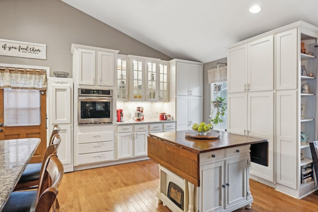 kitchen with tasteful backsplash, lofted ceiling, oven, light hardwood / wood-style floors, and white cabinets