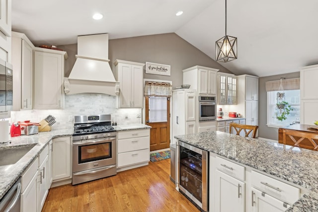 kitchen featuring premium range hood, stainless steel appliances, tasteful backsplash, wine cooler, and white cabinets