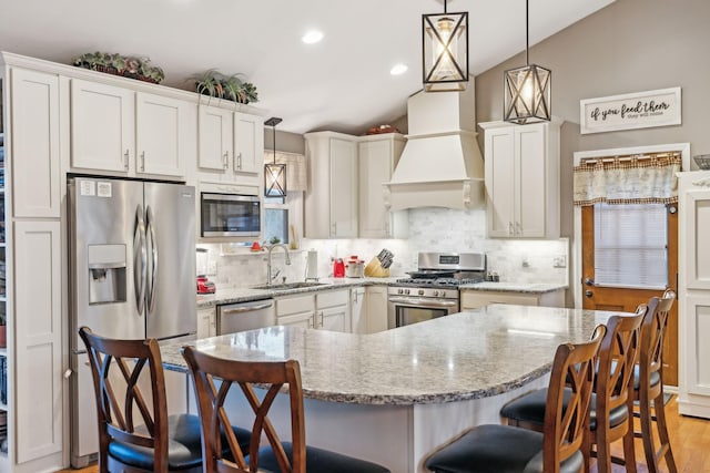 kitchen with appliances with stainless steel finishes, sink, pendant lighting, and custom range hood