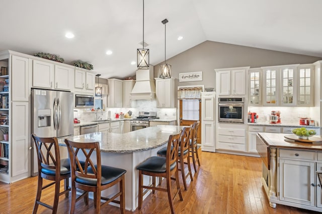 kitchen featuring appliances with stainless steel finishes, backsplash, custom range hood, white cabinets, and a center island