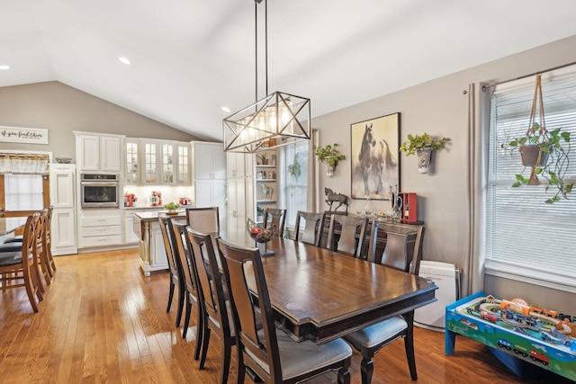 dining area featuring lofted ceiling, a chandelier, and light hardwood / wood-style floors