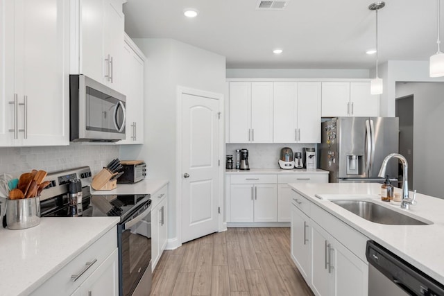 kitchen with white cabinetry, stainless steel appliances, backsplash, decorative light fixtures, and sink