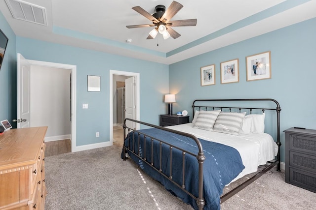 bedroom with ceiling fan, a raised ceiling, and carpet floors