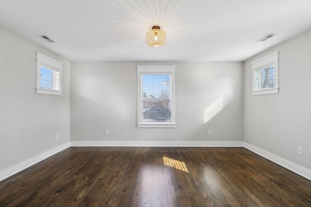 empty room with dark hardwood / wood-style flooring and a healthy amount of sunlight