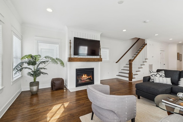 living room featuring dark wood-type flooring, a fireplace, and crown molding