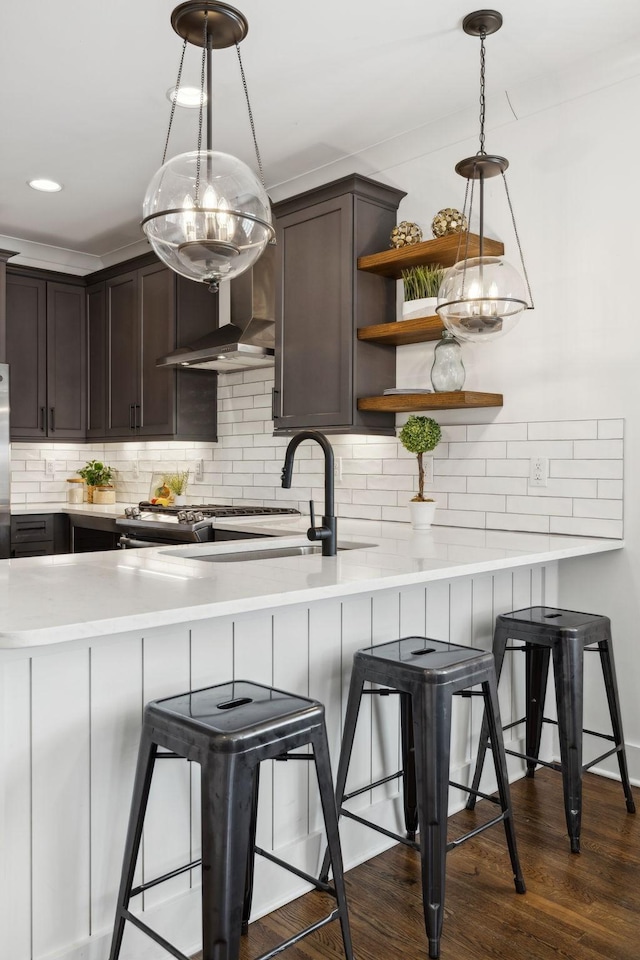 kitchen featuring dark hardwood / wood-style floors, decorative light fixtures, a breakfast bar, and kitchen peninsula