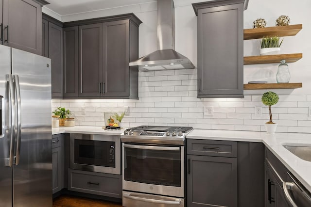 kitchen featuring tasteful backsplash, light stone countertops, appliances with stainless steel finishes, and wall chimney exhaust hood