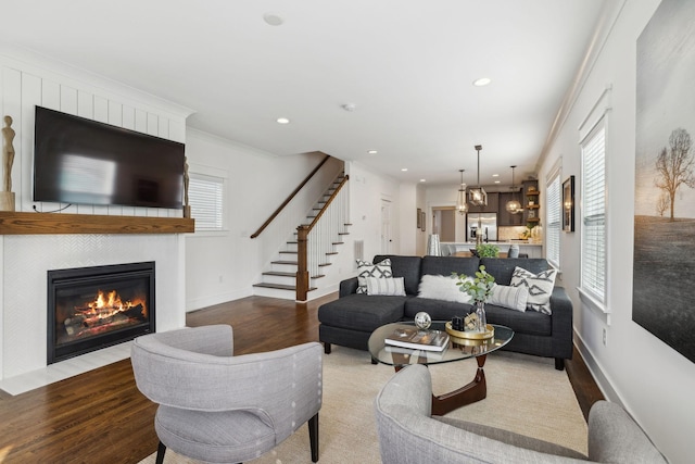 living room with crown molding, a fireplace, and light wood-type flooring