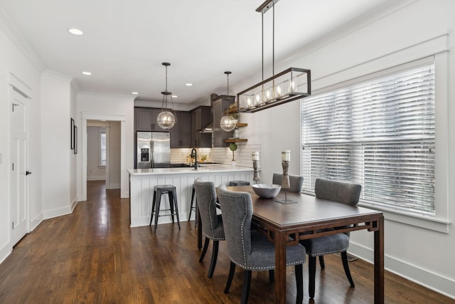 dining space featuring crown molding, dark wood-type flooring, and sink