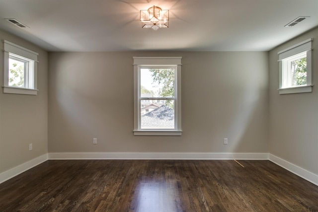 empty room featuring a healthy amount of sunlight and dark wood-type flooring