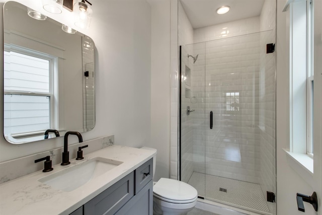 bathroom featuring vanity, toilet, and a shower with shower door