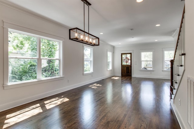 interior space with ornamental molding, a notable chandelier, and dark hardwood / wood-style flooring