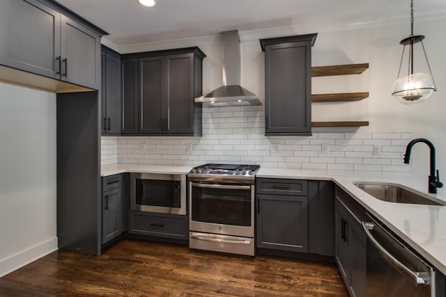 kitchen with appliances with stainless steel finishes, decorative light fixtures, sink, dark hardwood / wood-style flooring, and wall chimney exhaust hood