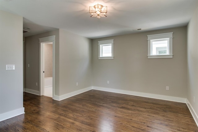 empty room with dark wood-type flooring and plenty of natural light