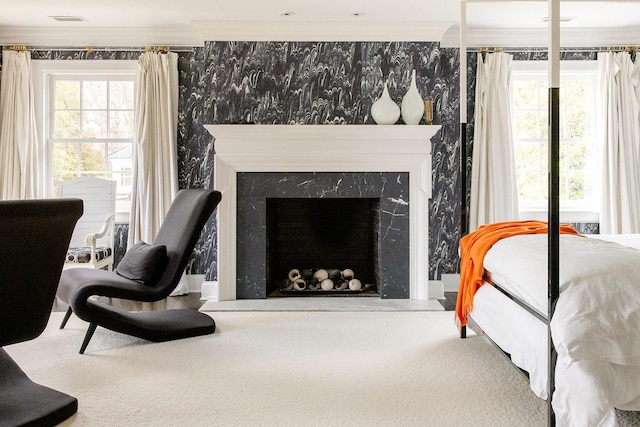 bedroom featuring a high end fireplace, crown molding, and multiple windows