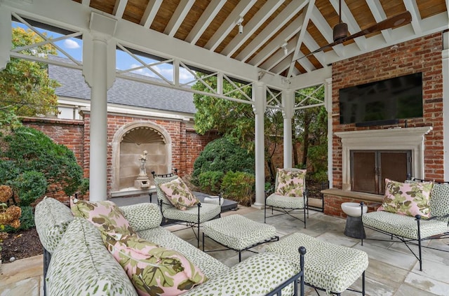 view of patio with an outdoor brick fireplace, a gazebo, and ceiling fan