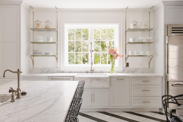 kitchen featuring light stone countertops, refrigerator, white cabinets, and sink