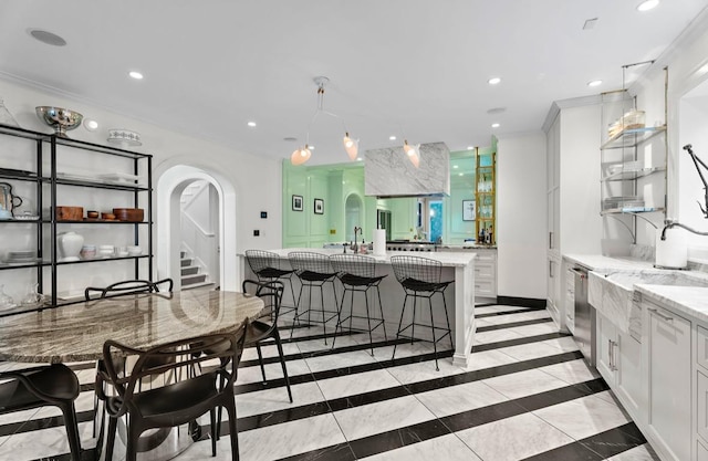 kitchen featuring a breakfast bar, white cabinetry, a spacious island, and light stone countertops