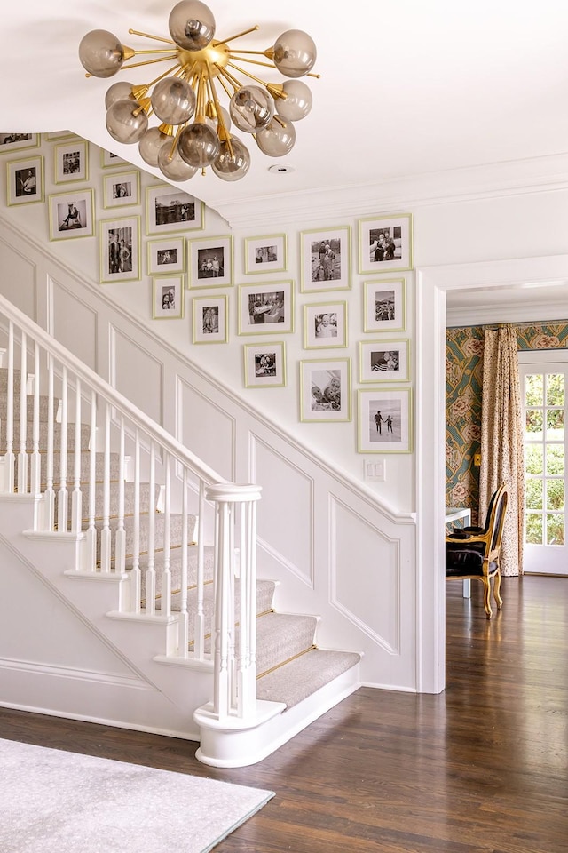 staircase featuring an inviting chandelier, ornamental molding, and hardwood / wood-style flooring