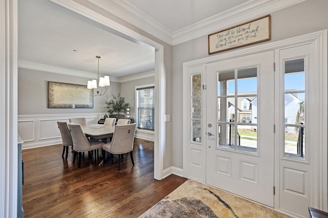 entrance foyer with dark hardwood / wood-style flooring, a wealth of natural light, an inviting chandelier, and ornamental molding