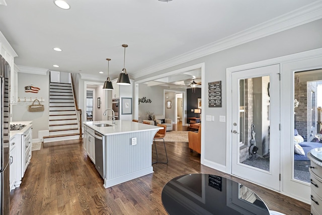 kitchen with white cabinets, appliances with stainless steel finishes, decorative light fixtures, sink, and a center island with sink