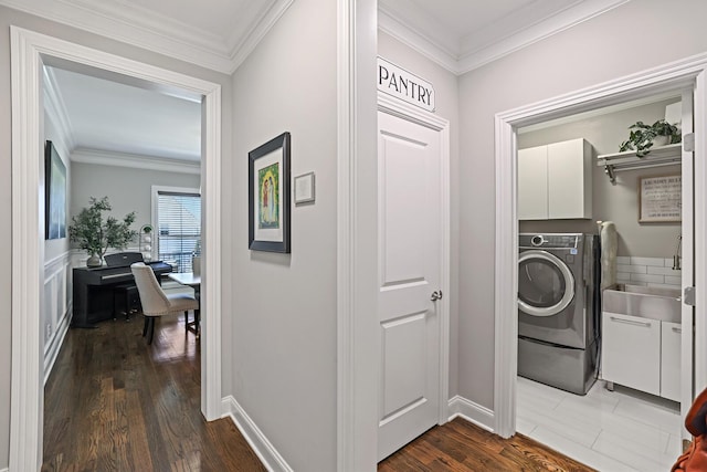 clothes washing area with crown molding, dark hardwood / wood-style floors, washer / dryer, and cabinets