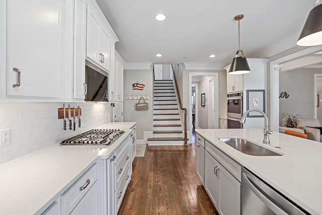 kitchen with white cabinets, appliances with stainless steel finishes, decorative light fixtures, sink, and backsplash