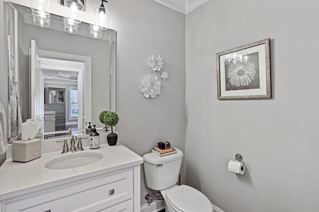 bathroom featuring toilet, vanity, and ornamental molding