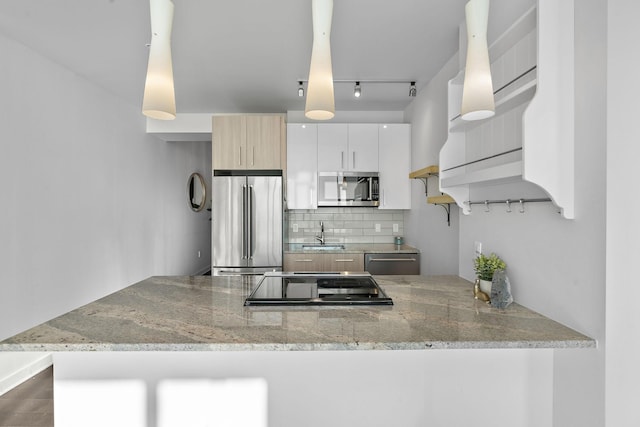 kitchen with white cabinetry, kitchen peninsula, stainless steel appliances, backsplash, and light stone counters