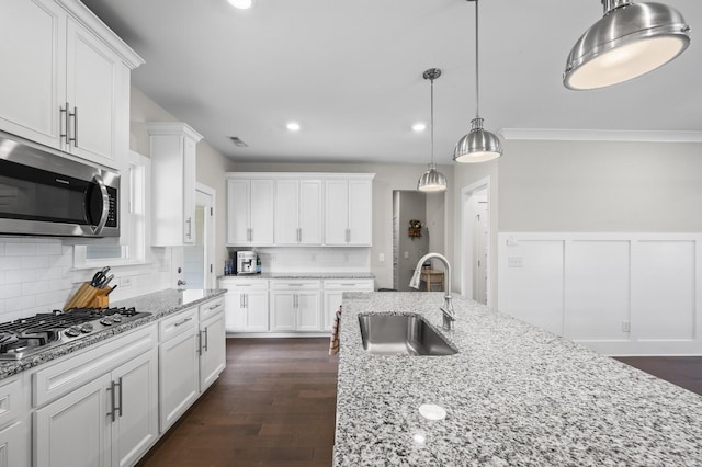 kitchen featuring sink, white cabinetry, stainless steel appliances, and hanging light fixtures