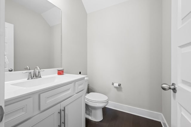 bathroom with hardwood / wood-style flooring, toilet, vanity, and lofted ceiling