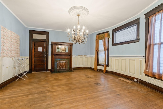 unfurnished dining area with light wood-type flooring, an inviting chandelier, and ornamental molding