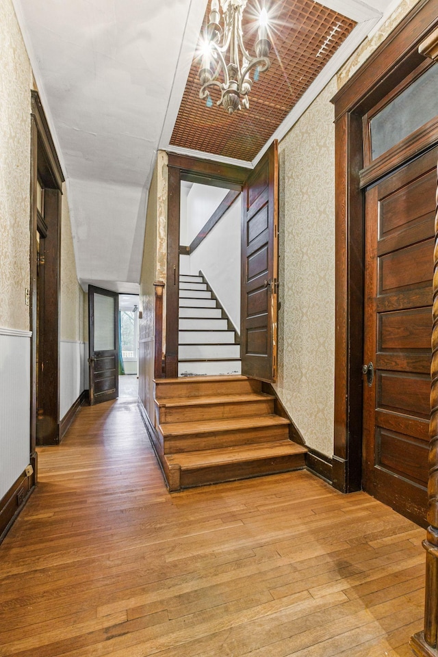 hall featuring hardwood / wood-style flooring, crown molding, and a notable chandelier