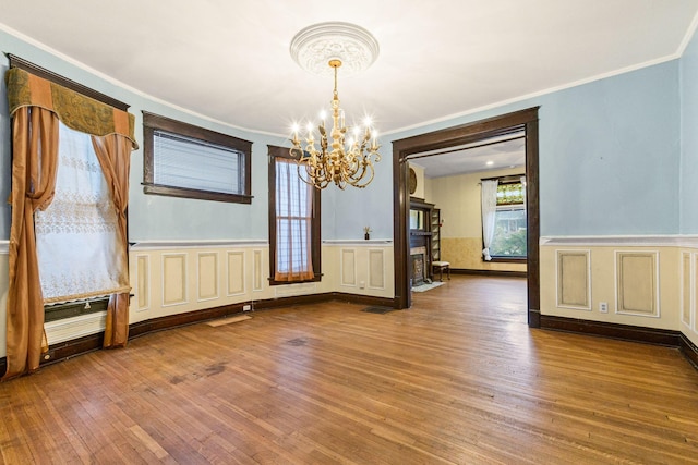 unfurnished dining area with wood-type flooring, ornamental molding, and a chandelier