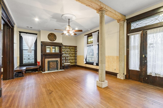 unfurnished living room with ceiling fan, light hardwood / wood-style flooring, ornate columns, and ornamental molding