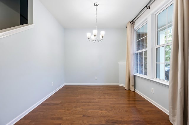 unfurnished dining area with dark hardwood / wood-style floors and a notable chandelier