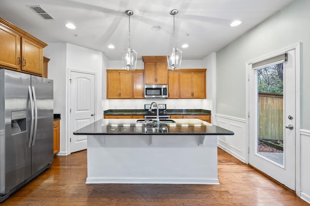 kitchen with a kitchen island with sink, sink, stainless steel appliances, and pendant lighting