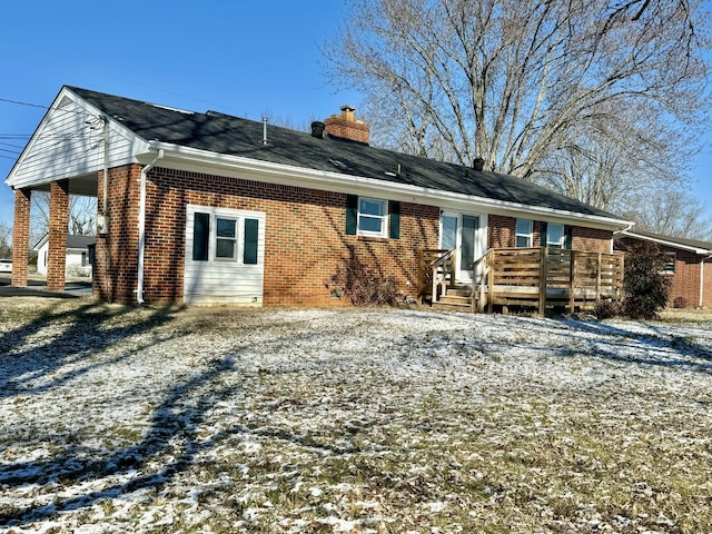 snow covered back of property with a wooden deck