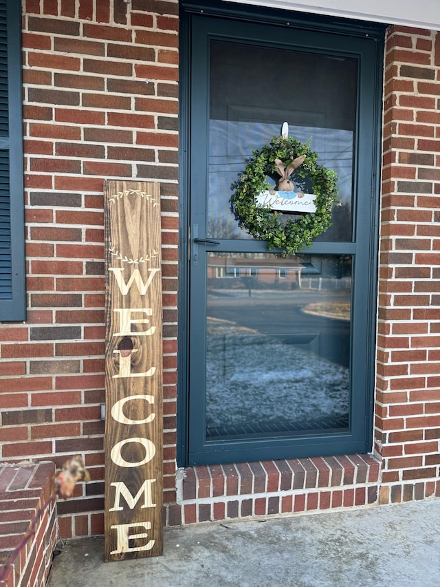 view of exterior entry featuring brick siding