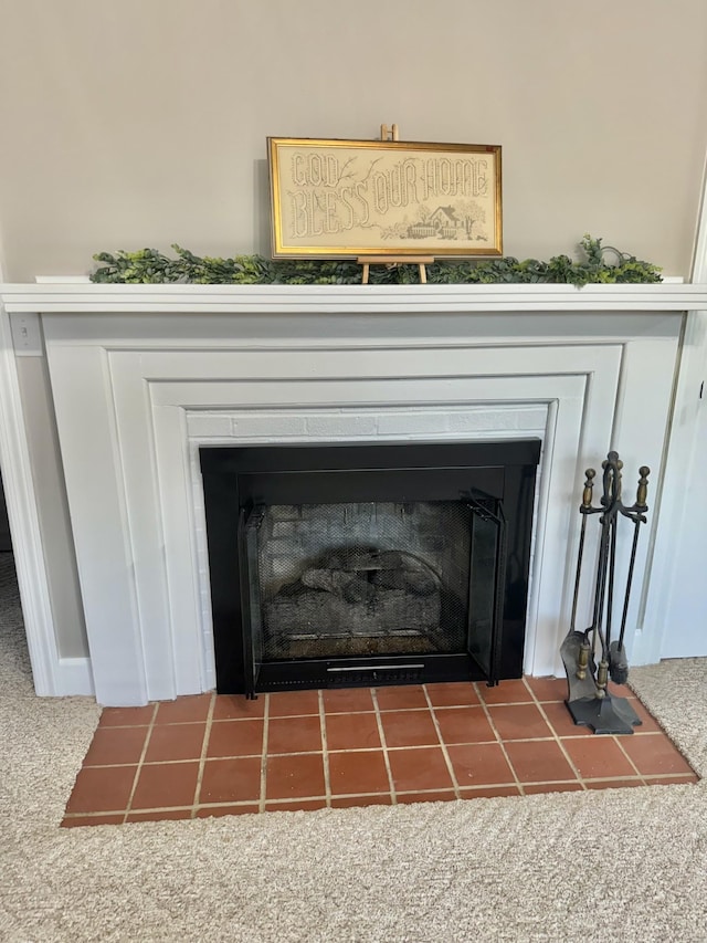 interior details featuring carpet and a tiled fireplace