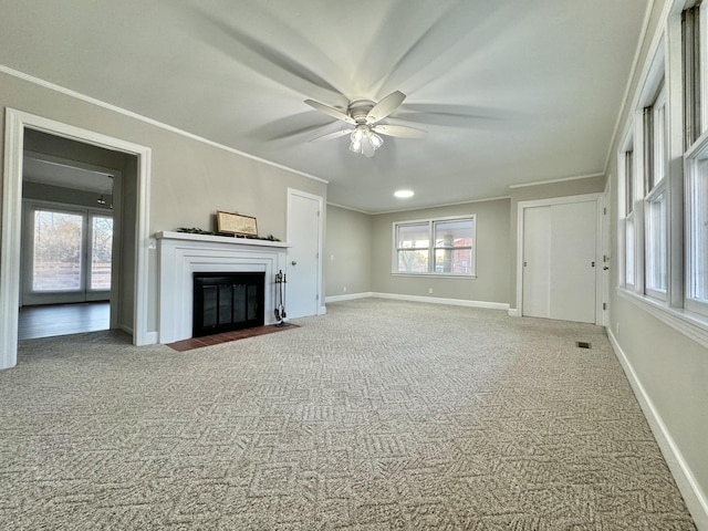 unfurnished living room featuring a fireplace with flush hearth, ornamental molding, carpet floors, and baseboards