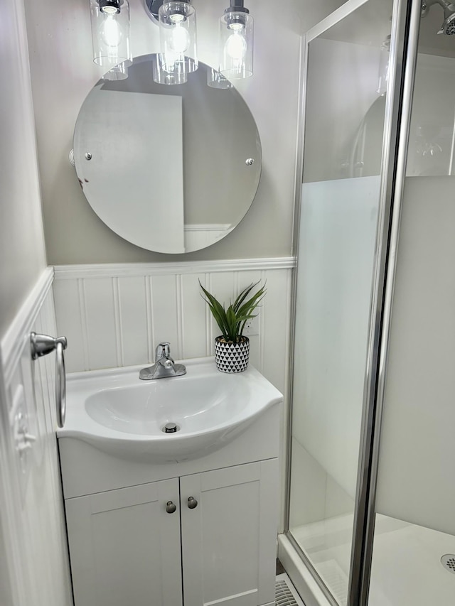 bathroom with a wainscoted wall, a decorative wall, vanity, and a shower stall