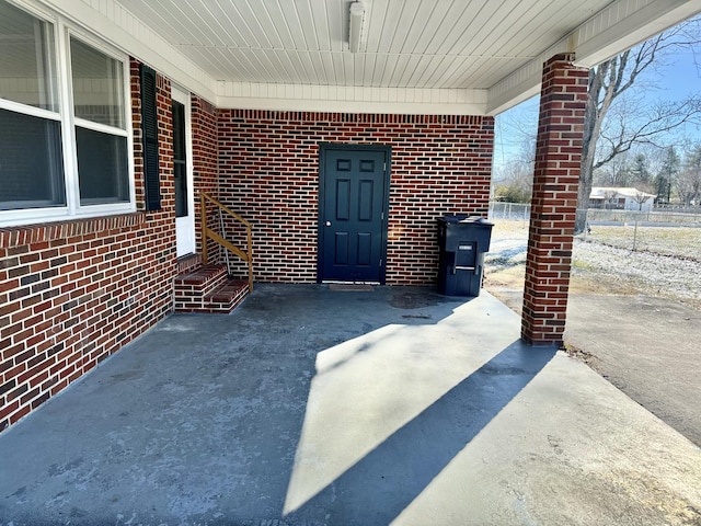 view of exterior entry featuring concrete driveway and brick siding