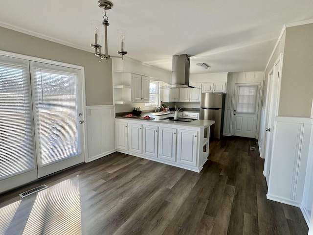 kitchen with island range hood, a peninsula, visible vents, freestanding refrigerator, and open shelves