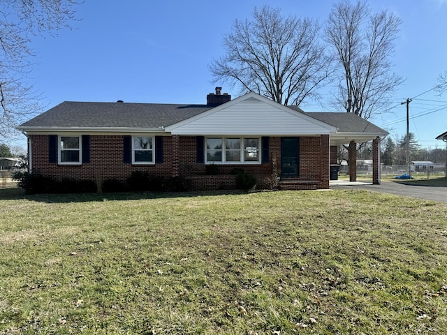 single story home with aphalt driveway, brick siding, roof with shingles, a chimney, and a front yard