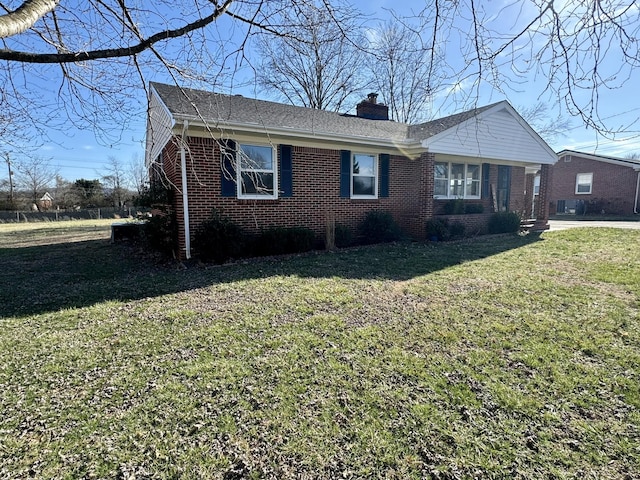 view of front of home featuring a front yard, brick siding, and a chimney