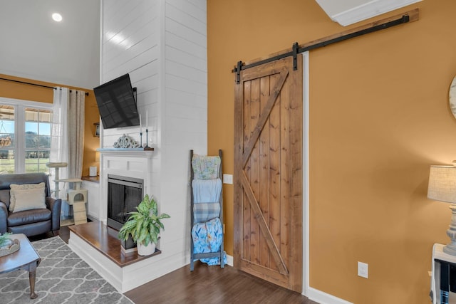 living room featuring a large fireplace, a barn door, and dark hardwood / wood-style flooring