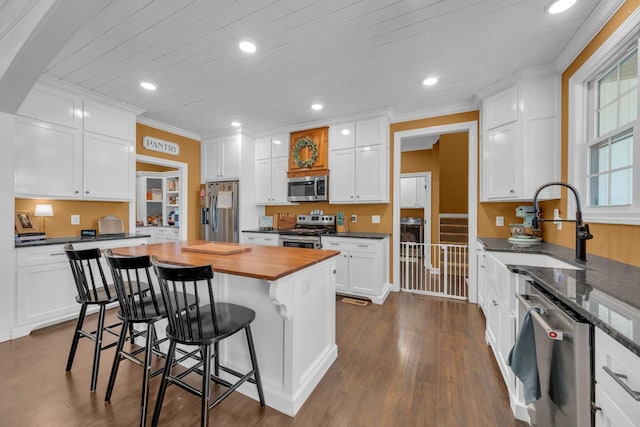 kitchen with a center island, crown molding, a breakfast bar area, stainless steel appliances, and white cabinets