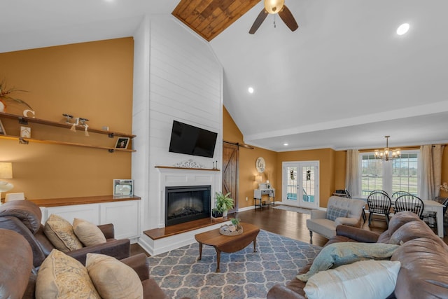 living room featuring ceiling fan with notable chandelier, wood-type flooring, french doors, a large fireplace, and high vaulted ceiling